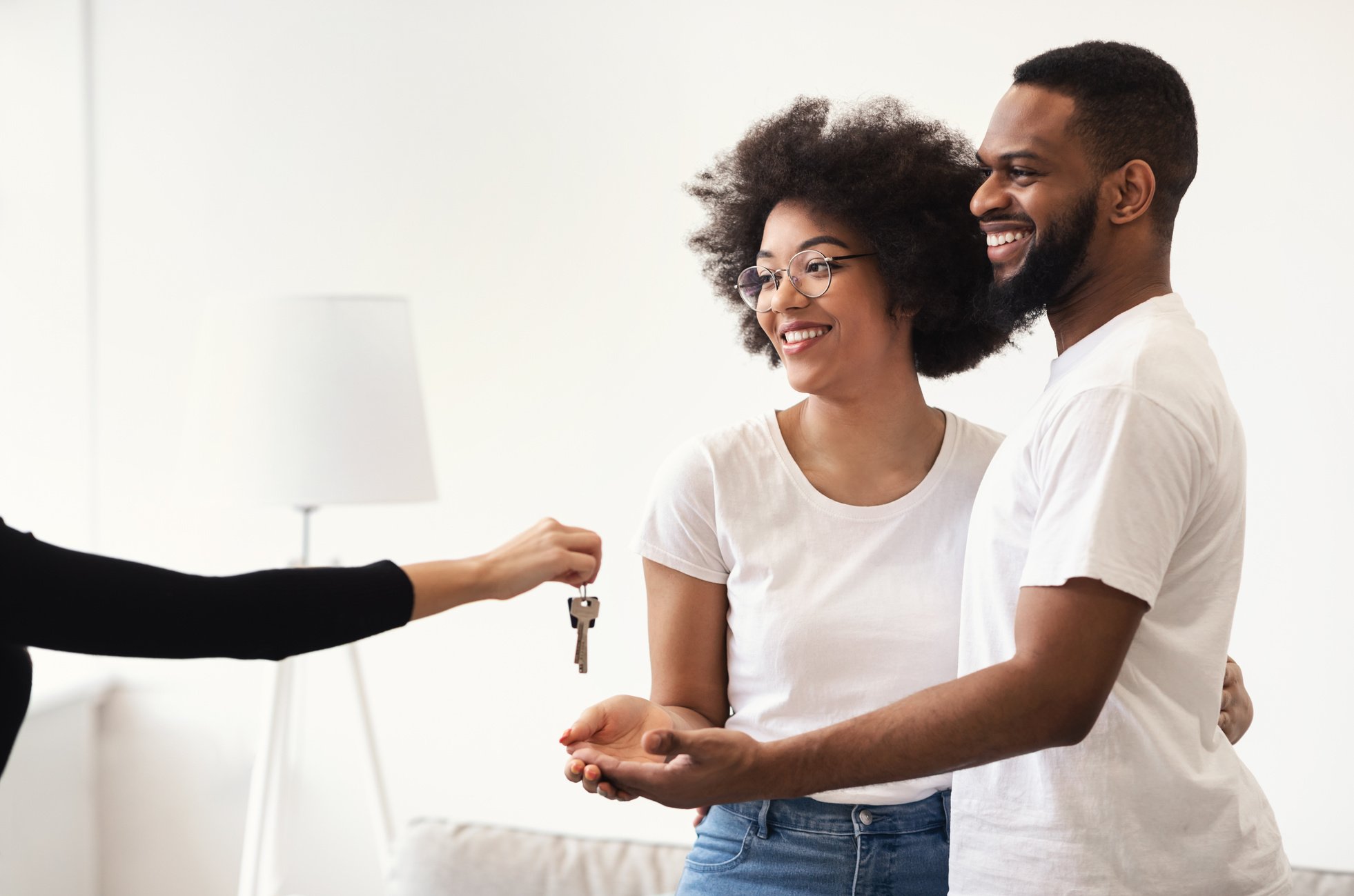 Real Estate Agent Giving House Key To Black Couple Indoors